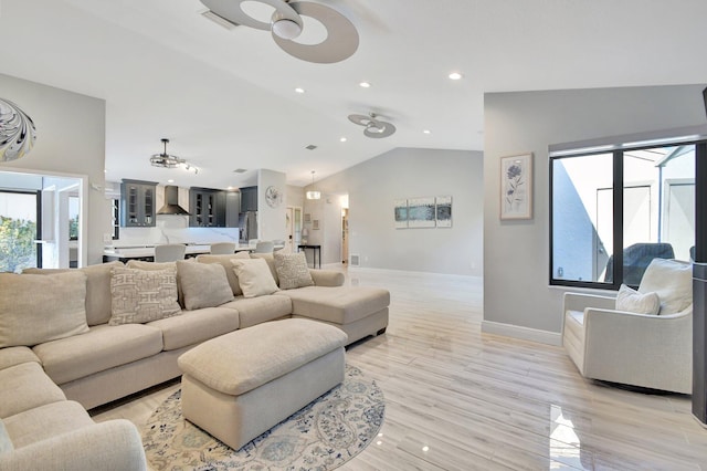 living room featuring light hardwood / wood-style flooring, vaulted ceiling, and ceiling fan