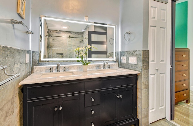 bathroom with vanity, wood-type flooring, a shower with door, and tile walls