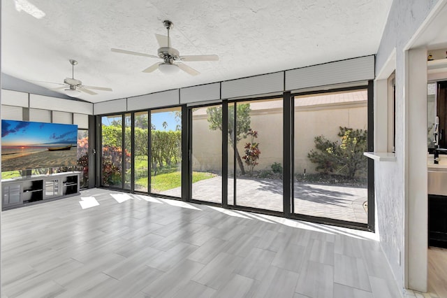 unfurnished living room featuring a textured ceiling, expansive windows, light hardwood / wood-style flooring, and ceiling fan