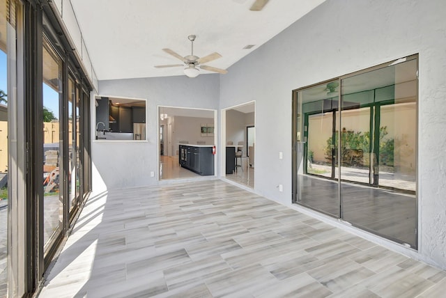 unfurnished sunroom featuring ceiling fan, plenty of natural light, and lofted ceiling