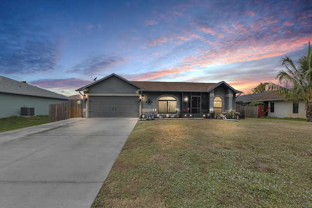 single story home featuring a garage, a yard, and central AC