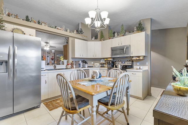 kitchen featuring light tile patterned floors, decorative light fixtures, ceiling fan with notable chandelier, and appliances with stainless steel finishes