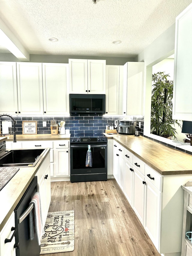 kitchen with appliances with stainless steel finishes, light hardwood / wood-style flooring, white cabinetry, and sink