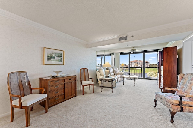 sitting room featuring light carpet, a textured ceiling, ceiling fan, and crown molding