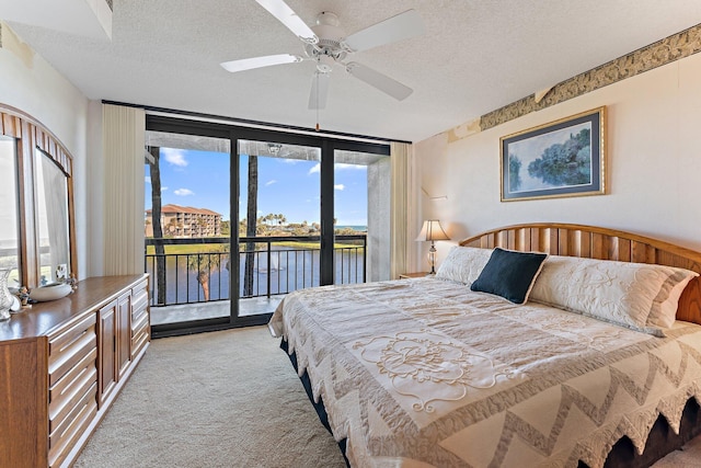 bedroom featuring ceiling fan, light colored carpet, a textured ceiling, access to outside, and a water view