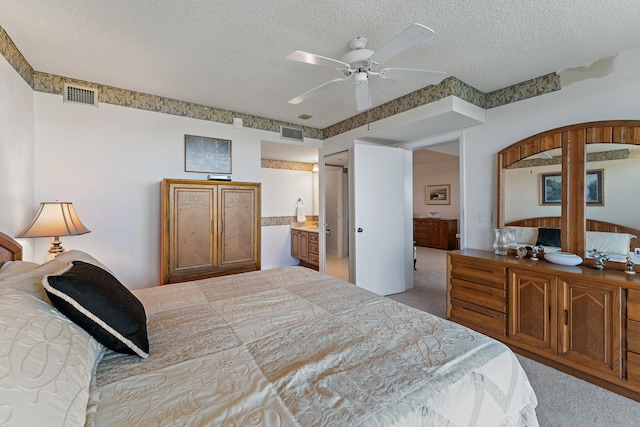 carpeted bedroom featuring a textured ceiling, connected bathroom, and ceiling fan