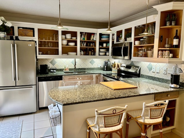 kitchen with kitchen peninsula, a kitchen breakfast bar, ornamental molding, stainless steel appliances, and decorative light fixtures