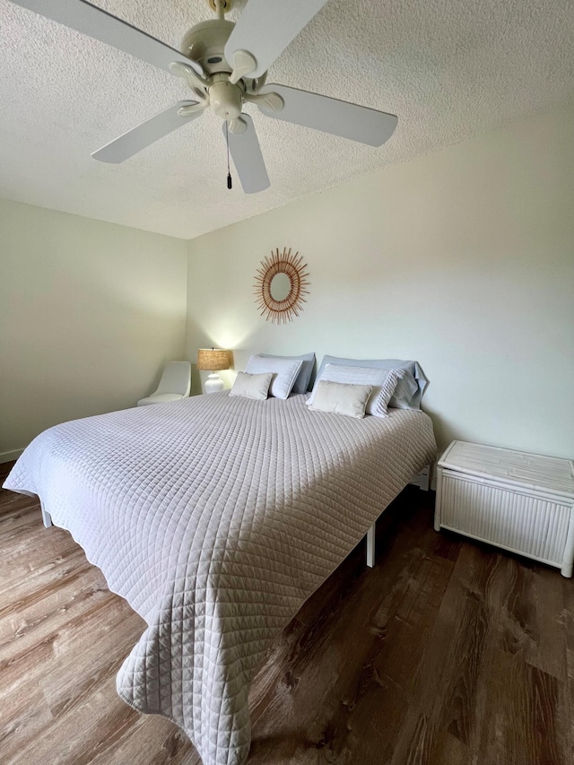 bedroom featuring ceiling fan, dark wood-type flooring, and a textured ceiling