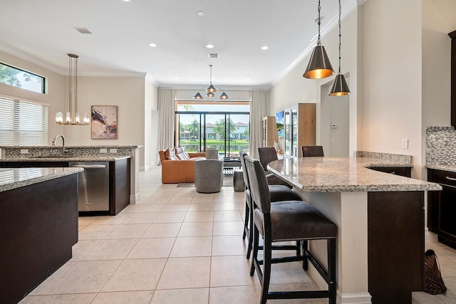 kitchen with light stone countertops, stainless steel dishwasher, hanging light fixtures, and crown molding