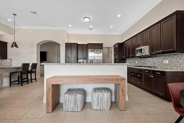 kitchen featuring decorative light fixtures, ornamental molding, stainless steel appliances, and an island with sink