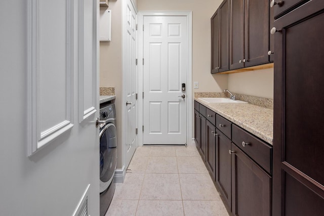 clothes washing area with light tile patterned flooring, cabinets, sink, and washer / clothes dryer