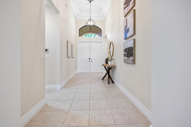 interior space with light tile patterned floors, a towering ceiling, and crown molding