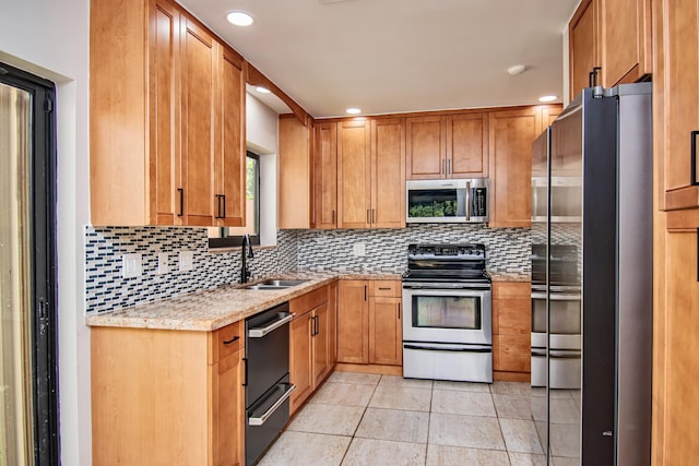 kitchen featuring light stone countertops, sink, appliances with stainless steel finishes, and tasteful backsplash