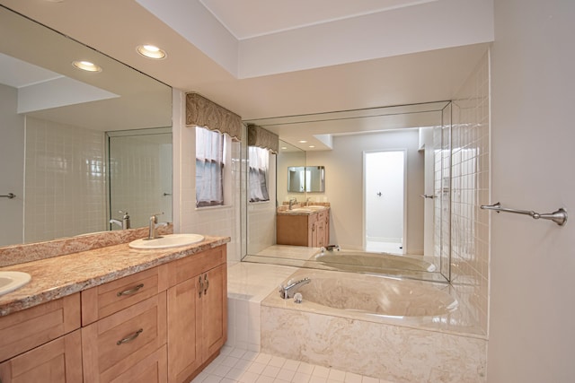 bathroom featuring tile patterned flooring, vanity, and tiled tub