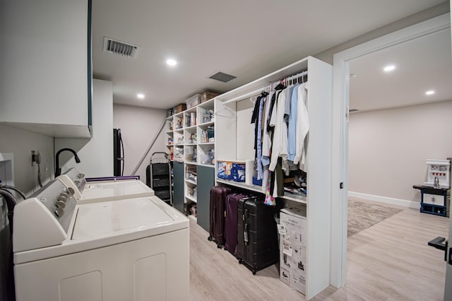 laundry room with washer and dryer, light hardwood / wood-style flooring, and cabinets