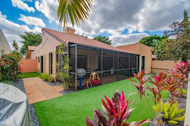 rear view of house featuring a lawn and a sunroom