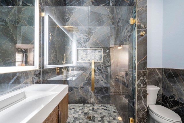 bathroom with vanity, a shower with shower door, tile walls, and toilet