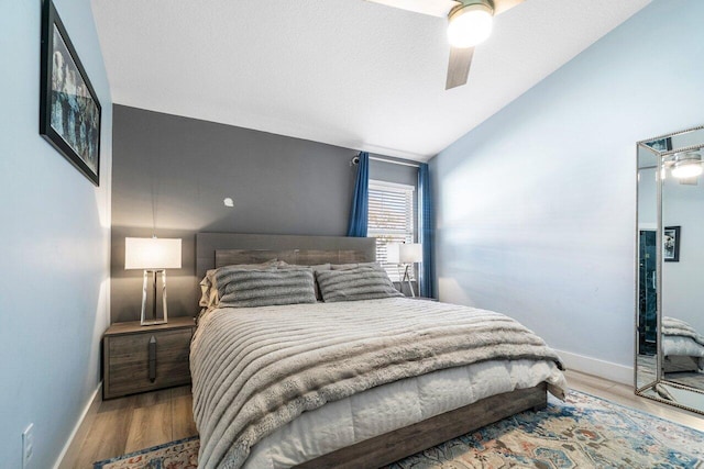 bedroom featuring light hardwood / wood-style floors, vaulted ceiling, and ceiling fan