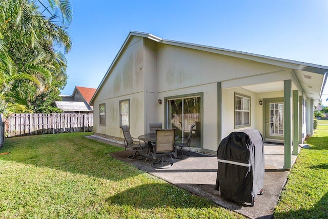 back of house with a lawn and a patio