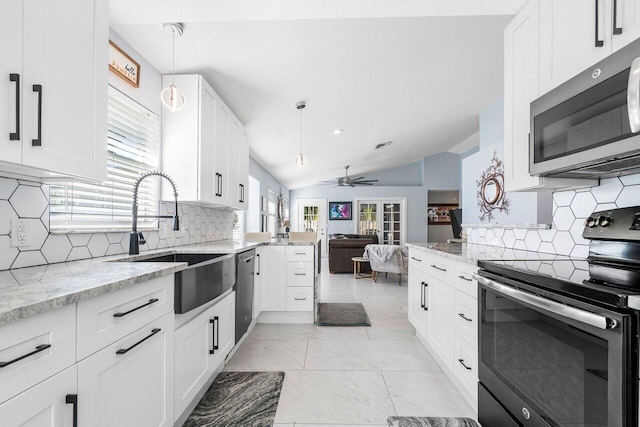 kitchen featuring white cabinets, appliances with stainless steel finishes, decorative light fixtures, and vaulted ceiling