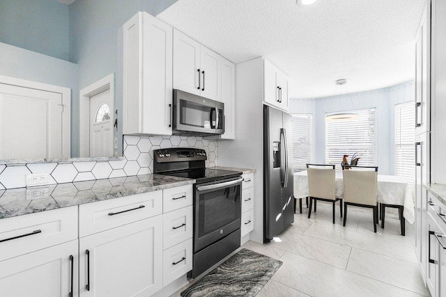 kitchen with backsplash, light stone countertops, a textured ceiling, appliances with stainless steel finishes, and white cabinetry