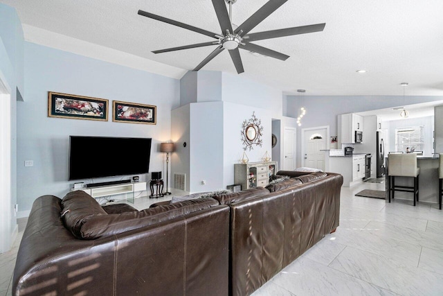 living room featuring a textured ceiling, ceiling fan, and vaulted ceiling