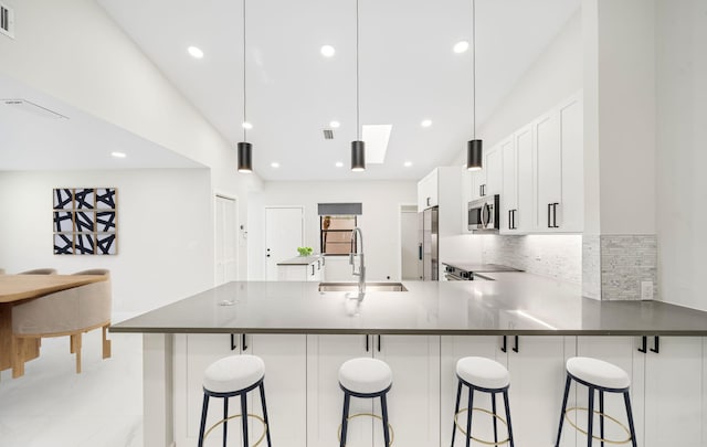 kitchen featuring white cabinets, a kitchen breakfast bar, sink, appliances with stainless steel finishes, and kitchen peninsula