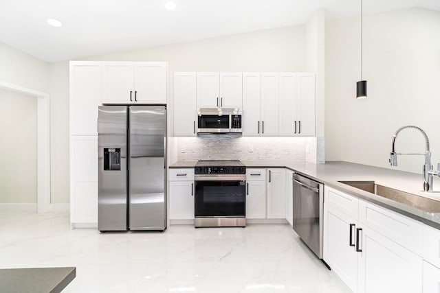 kitchen featuring decorative light fixtures, stainless steel appliances, vaulted ceiling, and sink