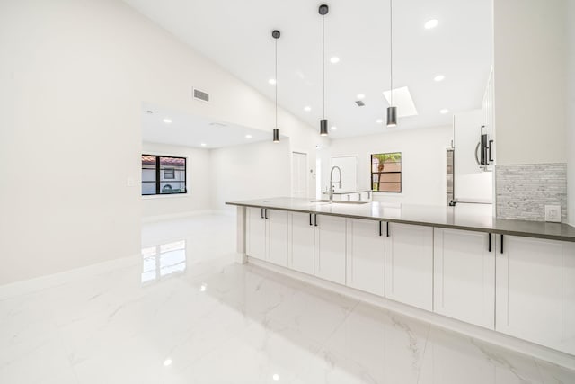 kitchen featuring backsplash, high vaulted ceiling, sink, decorative light fixtures, and white cabinetry