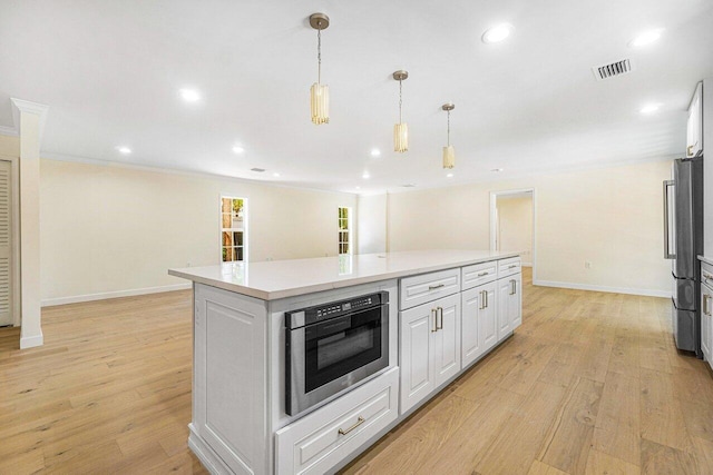 kitchen featuring a center island, light hardwood / wood-style flooring, crown molding, decorative light fixtures, and white cabinets