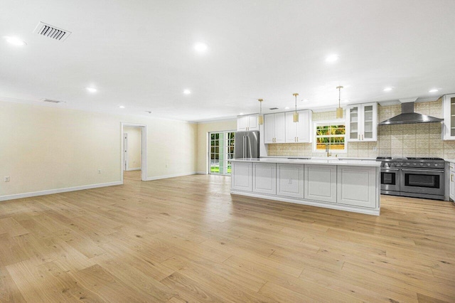 kitchen featuring plenty of natural light, a center island, stainless steel appliances, and wall chimney range hood