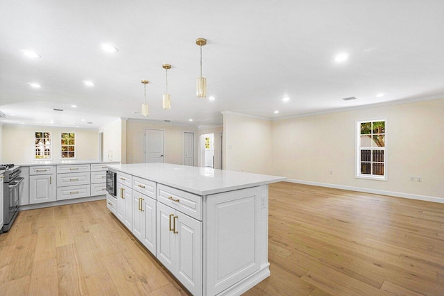 kitchen with light wood-type flooring, decorative light fixtures, white cabinetry, and a kitchen island