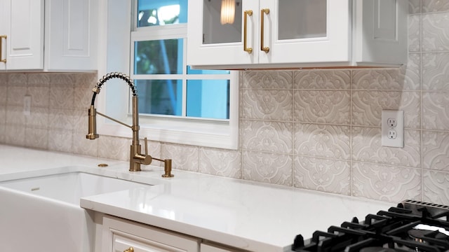 kitchen featuring tasteful backsplash, white cabinetry, sink, and gas cooktop