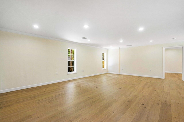 empty room featuring light wood-type flooring and ornamental molding