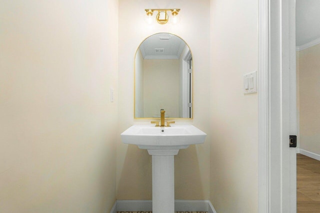 bathroom with wood-type flooring and crown molding