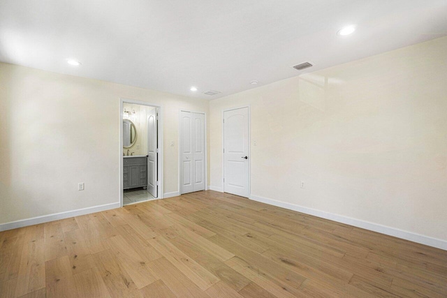 unfurnished bedroom featuring light wood-type flooring and connected bathroom