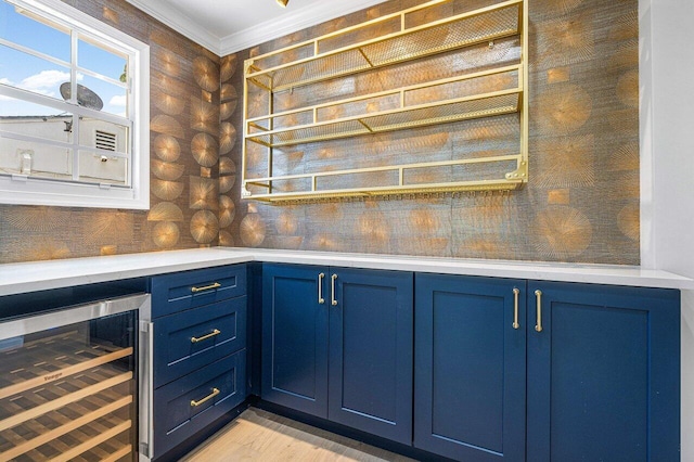 kitchen featuring light hardwood / wood-style floors, blue cabinets, crown molding, and beverage cooler