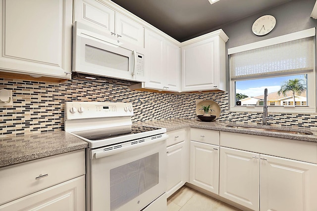 kitchen featuring white appliances, backsplash, white cabinets, sink, and light stone countertops