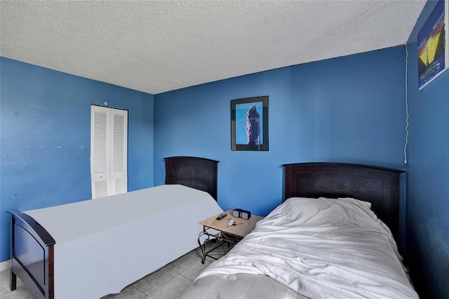 bedroom with light tile patterned floors, a textured ceiling, and a closet