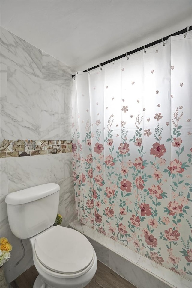 bathroom featuring wood-type flooring, tile walls, and toilet