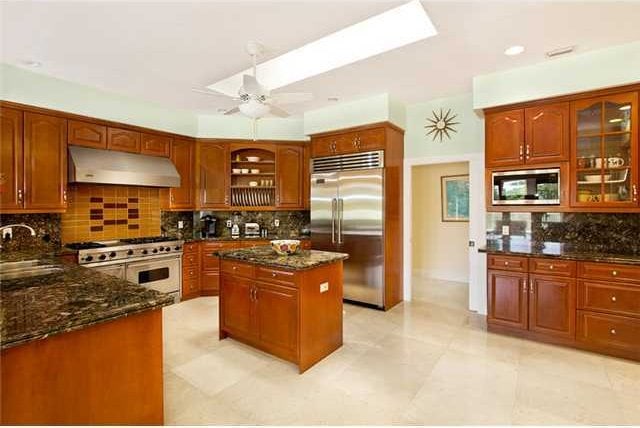 kitchen featuring decorative backsplash, premium appliances, a kitchen island, and dark stone counters