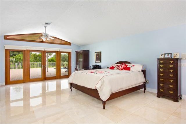 tiled bedroom with ceiling fan, french doors, access to outside, and vaulted ceiling