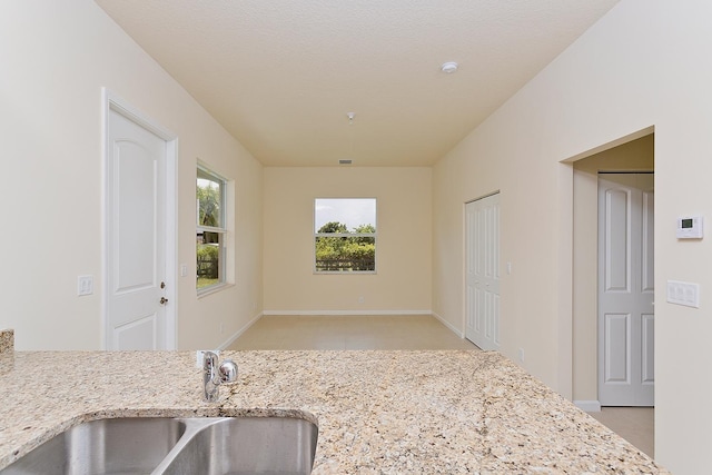 kitchen featuring light stone counters, sink, and a textured ceiling