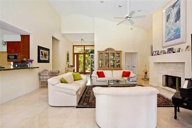 tiled living room featuring a stone fireplace, ceiling fan, and high vaulted ceiling