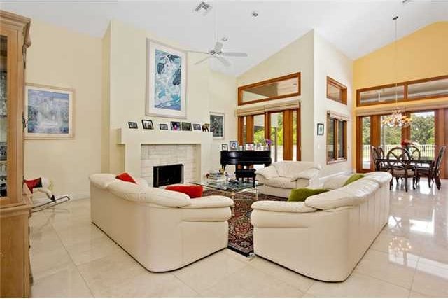 tiled living room with ceiling fan with notable chandelier and high vaulted ceiling