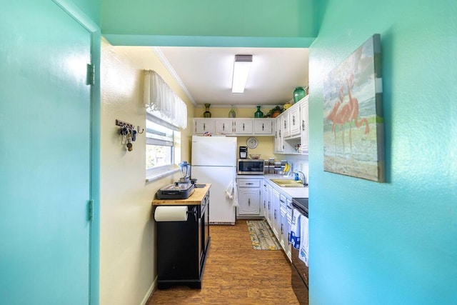 kitchen with crown molding, dark wood-type flooring, sink, white refrigerator, and white cabinets