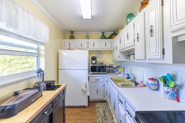 kitchen with white cabinets, sink, ornamental molding, white fridge, and butcher block counters