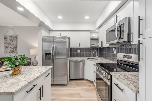 kitchen featuring backsplash, white cabinets, sink, light stone counters, and stainless steel appliances