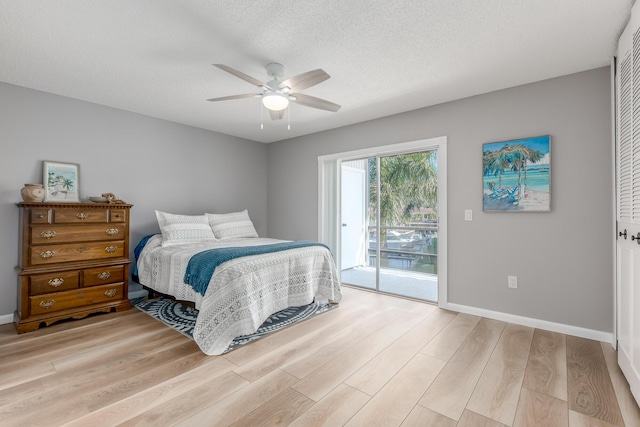 bedroom with ceiling fan, light hardwood / wood-style floors, a textured ceiling, and access to outside