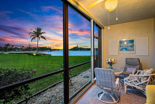 sunroom / solarium featuring ceiling fan and a water view